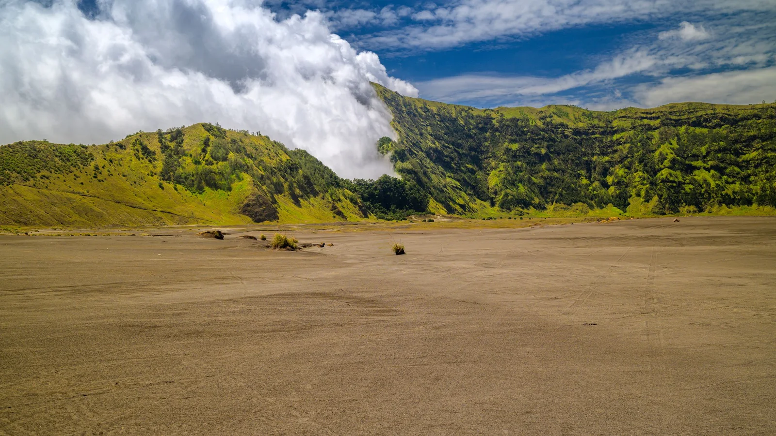 The smoking crater of Mount Bromo with Mount Semeru behind